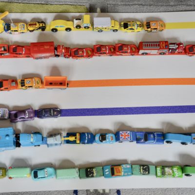 Cars lined up by colour on a sheet of cardboard